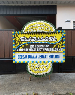 Papan Bunga Duka di Punggung Lading